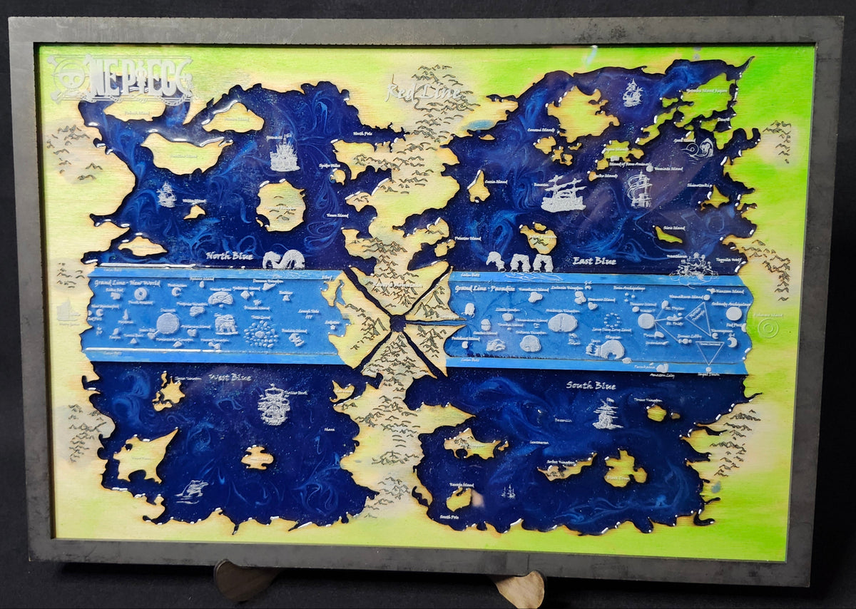 A framed art piece featuring a stylized map design with deep blue landmasses, a bright blue horizontal band, and a pale yellow-green background, displayed on a stand against a dark backdrop.